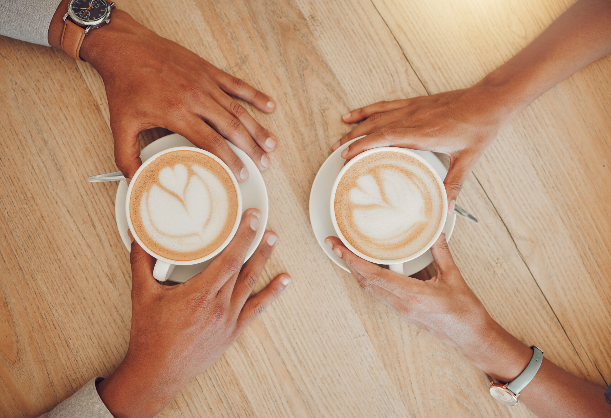Two hands across a table with coffee cups 