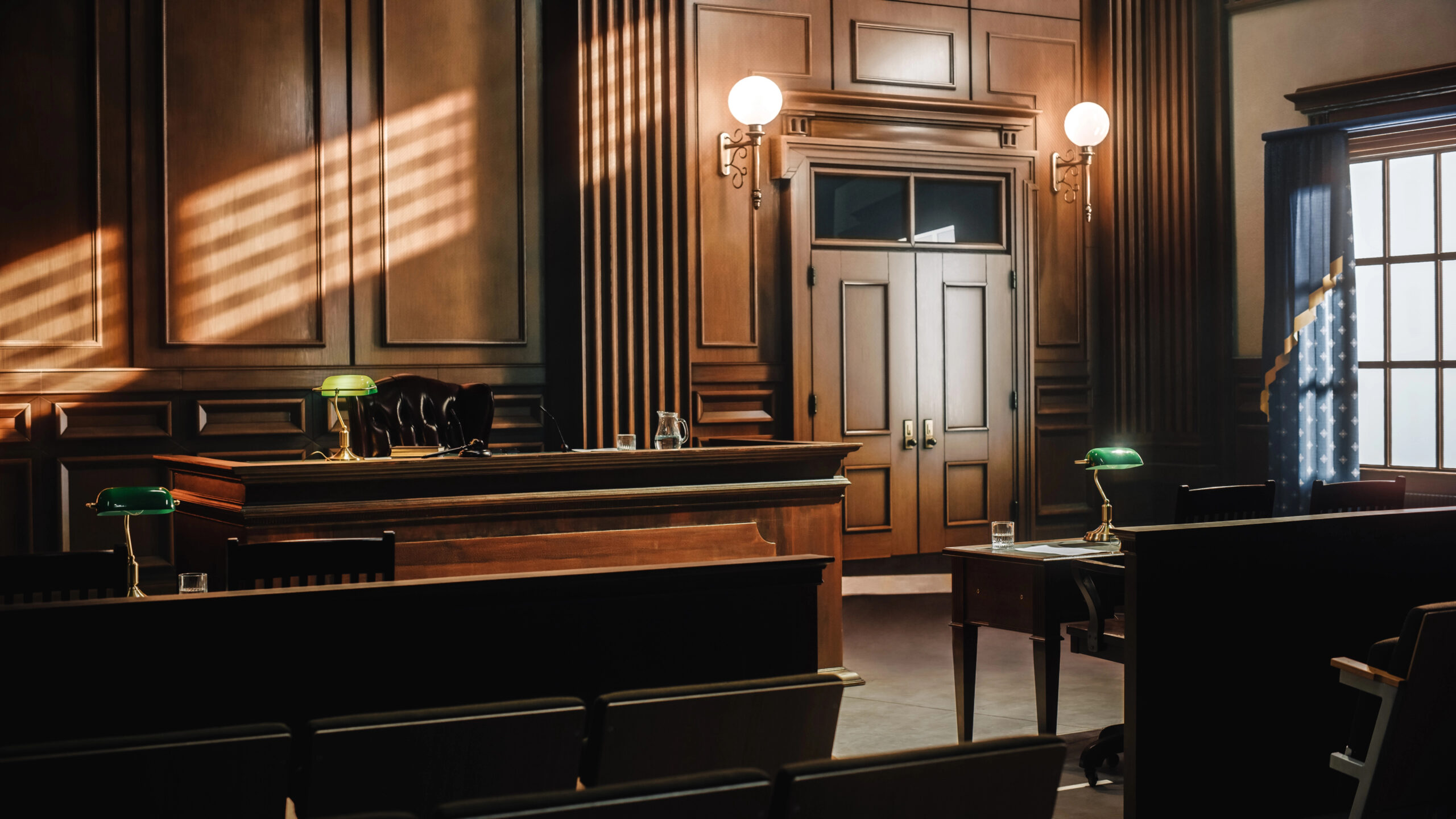 Empty Courtroom that shows the Judge's bench and the two attorney tables with light streaming in from the window