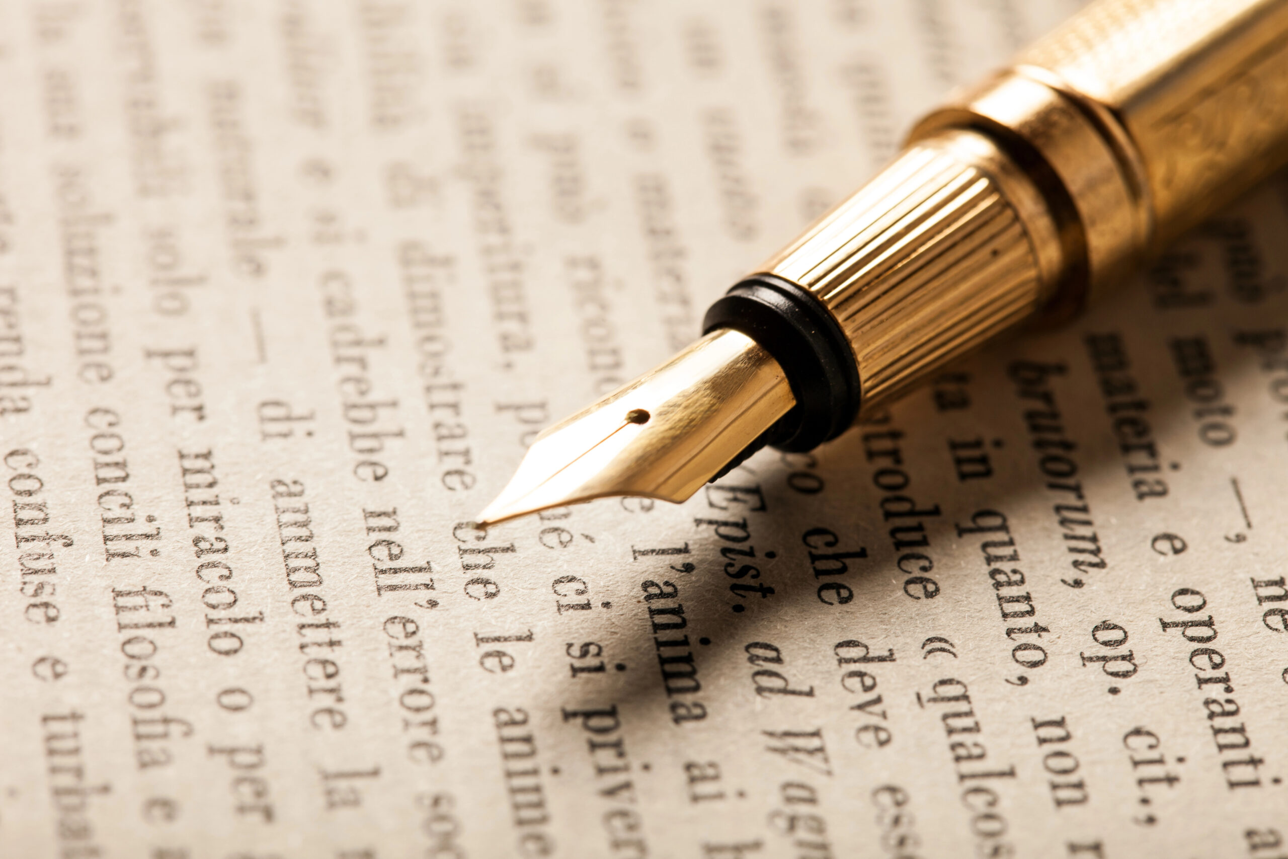 Gold fountain pen laying on latin written page of a book