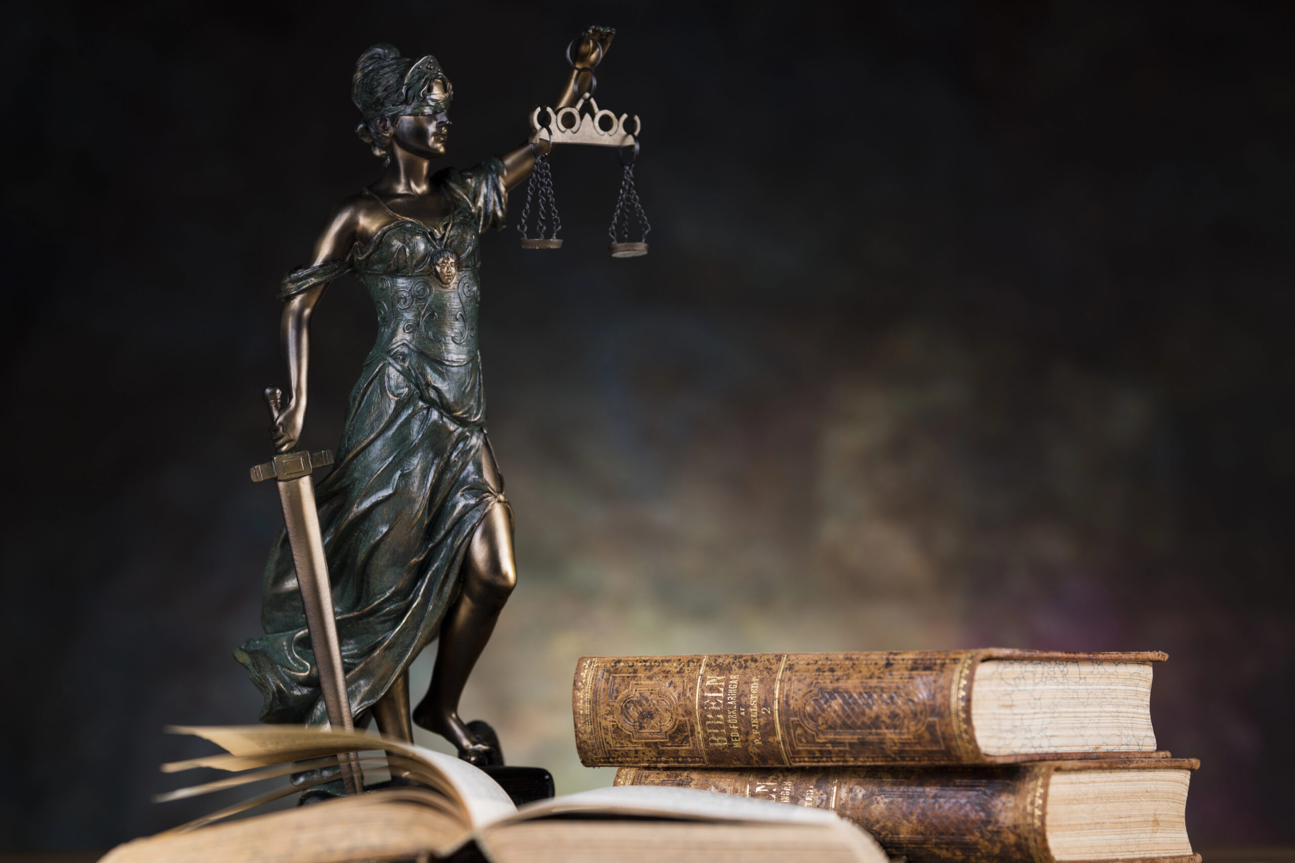 law books with a lady justice holding the scales of justice